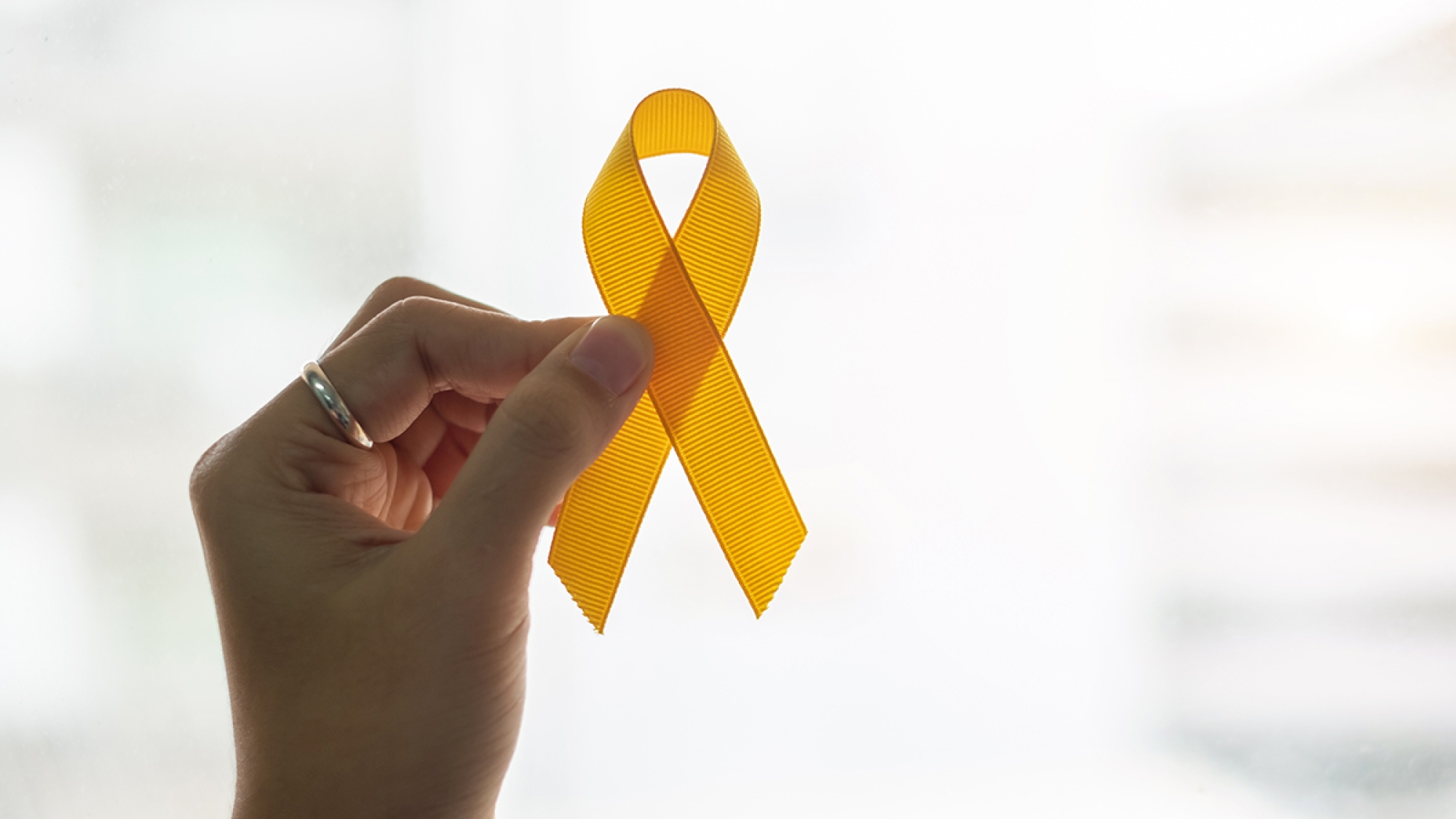 Suicide prevention and Childhood Cancer Awareness, Yellow Ribbon on wooden background for supporting people living and illness. children Healthcare and World cancer day concept