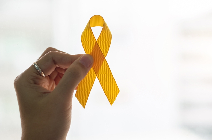 Suicide prevention and Childhood Cancer Awareness, Yellow Ribbon on wooden background  for supporting people living and illness. children Healthcare and World cancer day concept